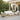 Outdoor patio set with wicker furniture and white cushions on a patio with a pergola and palm trees in the background.